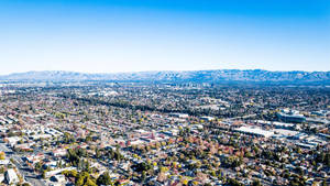 An Aerial View Of A City With Mountains In The Background Wallpaper