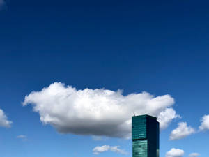 Azure Cloudy Sky With Green Building Wallpaper
