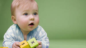 Baby Boy Playing With Colourful Blocks Wallpaper