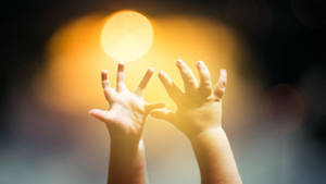 Baby Hands Reaching A Yellow Light Wallpaper