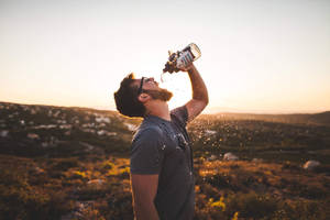 Bearded Guy Drinking Water From Bottle Wallpaper