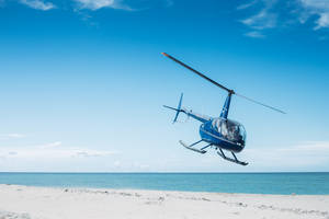 Blue Helicopter Landing On Sand Wallpaper