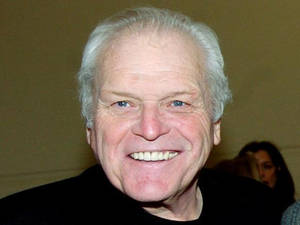 Brian Dennehy Smiling On Brown Background Wallpaper