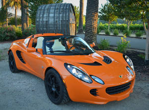 Bright Orange Lotus Convertible Against A Scenic View Wallpaper