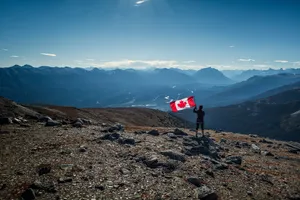 Canadian Flag And Person On Mountain Wallpaper