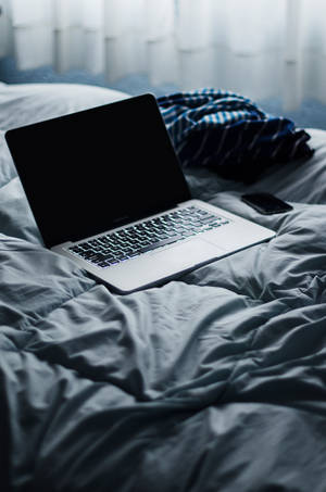 Caption: A Silver Macbook Pro On A White Desk With An Illuminated Keyboard And A Dark Background Wallpaper