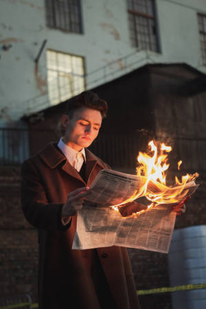 Caption: Daring Stylish Man Holding A Burning Newspaper Wallpaper