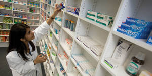 Caption: Dedicated Female Pharmacist Engaged In Medicine Check Wallpaper
