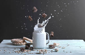 Caption: Delicious Fudge Brownies Splashing Into Fresh Milk Wallpaper