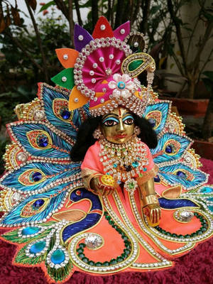 Caption: Divine Laddu Gopal Statue In Vibrant Orange And Blue Wallpaper