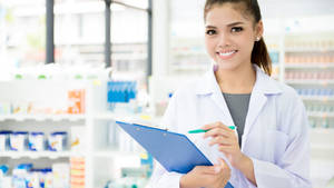 Caption: Female Pharmacist Analyzing Patients' Records Wallpaper