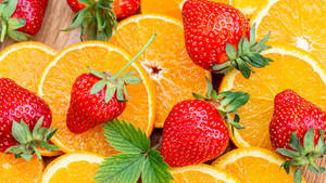 Caption: Fresh Orange Fruits With Ripe Red Strawberries Wallpaper