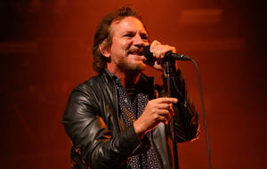 Caption: Iconic Pearl Jam's Lead Vocalist, Eddie Vedder In Live Rock Band Performance Wallpaper