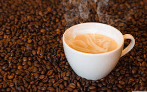 Caption: Invigorating Steaming Coffee Cup Resting On Raw Arabica Coffee Beans. Wallpaper