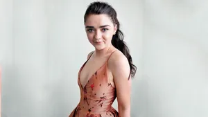 Caption: Maisie Williams Wearing A Formal Dress And Smiling At The Camera During An Event Wallpaper