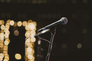 Caption: Retro Microphone Bathed In Warm Stage Lights Wallpaper