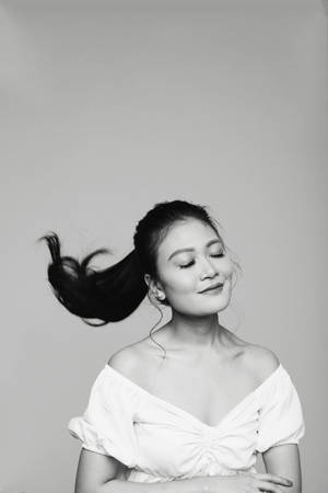 Caption: Striking Monochrome Portrait Of A Woman Flipping Her Ponytail Hair Wallpaper