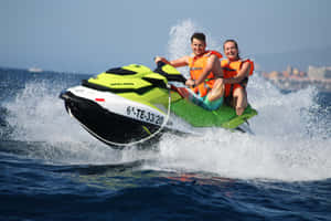 Caption: Thrill-seeking Couple Accelerating Their Jet Ski On Crystal Clear Waters Wallpaper