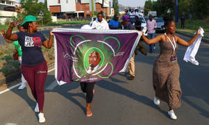 Caption: Vibrant Culture Of Lesotho - Women In Traditional Dress With King Letsie Iii Banner Wallpaper