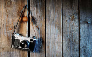 Caption: Vintage Camera Hanging From A Wooden Beam Wallpaper