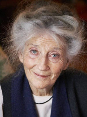 Captivating Elegance: A Beautiful Older Woman In A Blue Jacket Wallpaper