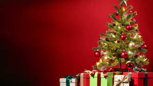 Celebrate Christmas In Style: A Stunning Christmas Tree With Wrapped Gifts Wallpaper