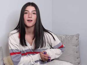 Charli Damelio Sitting On A Sofa Wallpaper