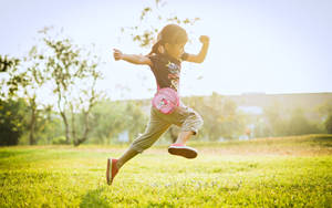 Child Jumping On The Grass Field Wallpaper