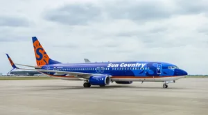 Cloudy Skies Over A Blue Aircraft Of Sun Country Wallpaper