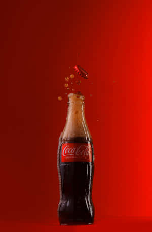 Coca Cola Bottle Falling On Red Background Wallpaper