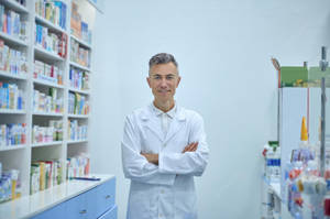 Confident Pharmacist In A White Lab Coat With Arms Folded Wallpaper