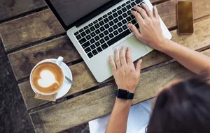 Confident Woman With Top-rated Laptop And Latte Art Coffee Wallpaper
