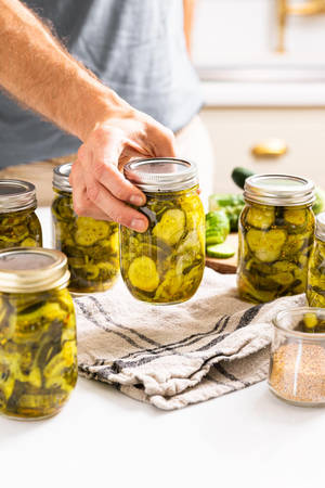Crispy Pickle Slices With Silver Jar Lid Wallpaper