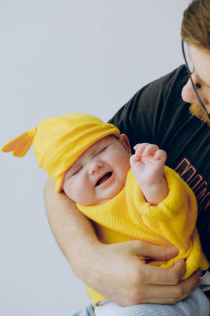 Cute Crying Baby In Yellow Outfit Wallpaper