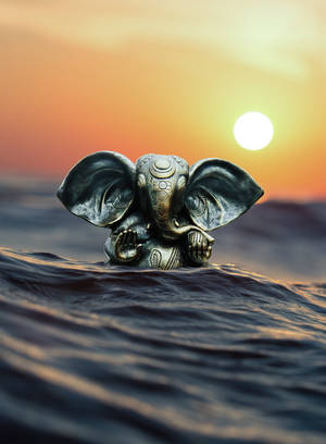 Cute Ganesha Silver Figurine On Ocean Wallpaper