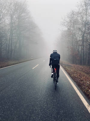 Cycling On Foggy Autumn Road Wallpaper