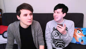 Dan And Phil Sitting On A Couch Wallpaper