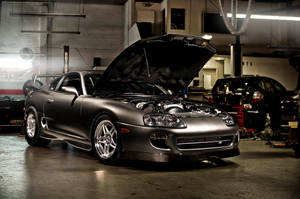 Dazzling Night View Of 4k Supra Car Against Cityscape Backdrop Wallpaper