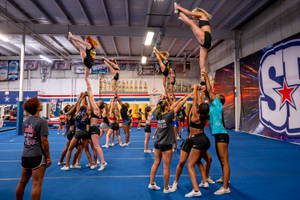 Dedicated Cheerleader Performing A Perfect Heel Stretch Wallpaper