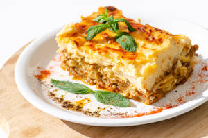 Delicious Slice Of Authentic Moussaka Garnished With Basil Wallpaper