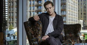 Elegance Personified - Joseph Quinn With Crossed Legs Wallpaper