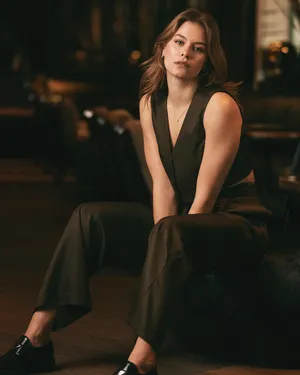 Elegant Sitting Womanin Vestand Trousers Wallpaper