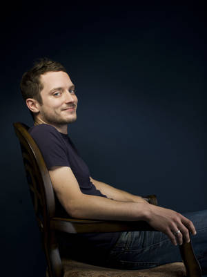 Elijah Wood Seated On A Chair Wallpaper