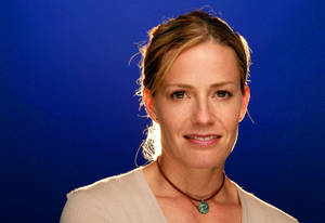 Elisabeth Shue Smiling With Hair Tied In Front Of Royal Blue Background Wallpaper