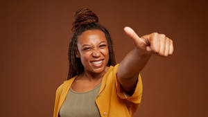 Empowered African Woman Giving Thumbs Up Wallpaper