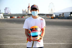 F1 Racer Yuki Tsunoda In Mask Holding Helmet Wallpaper