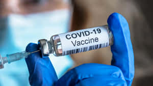 Female Doctor Holding Covid-19 Vaccine Wallpaper