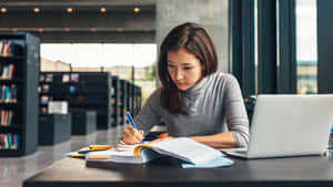 Focused Student Studying With Laptop And Books.jpg Wallpaper