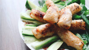 Freshly Made Egg Rolls Stacked On Sliced Cucumbers Wallpaper