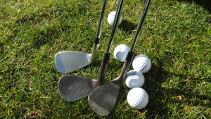 Golf Club Heads And Balls On Golf Course Wallpaper